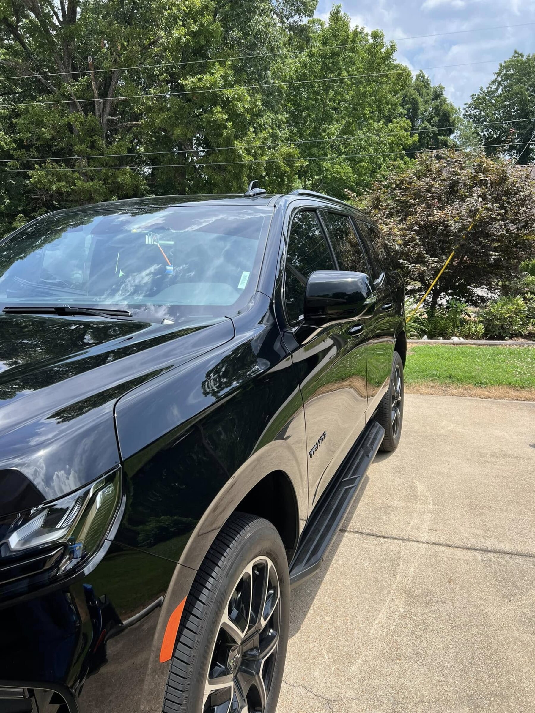 A gloss black Chevrolet Tahoe detailed in a customer's driveway