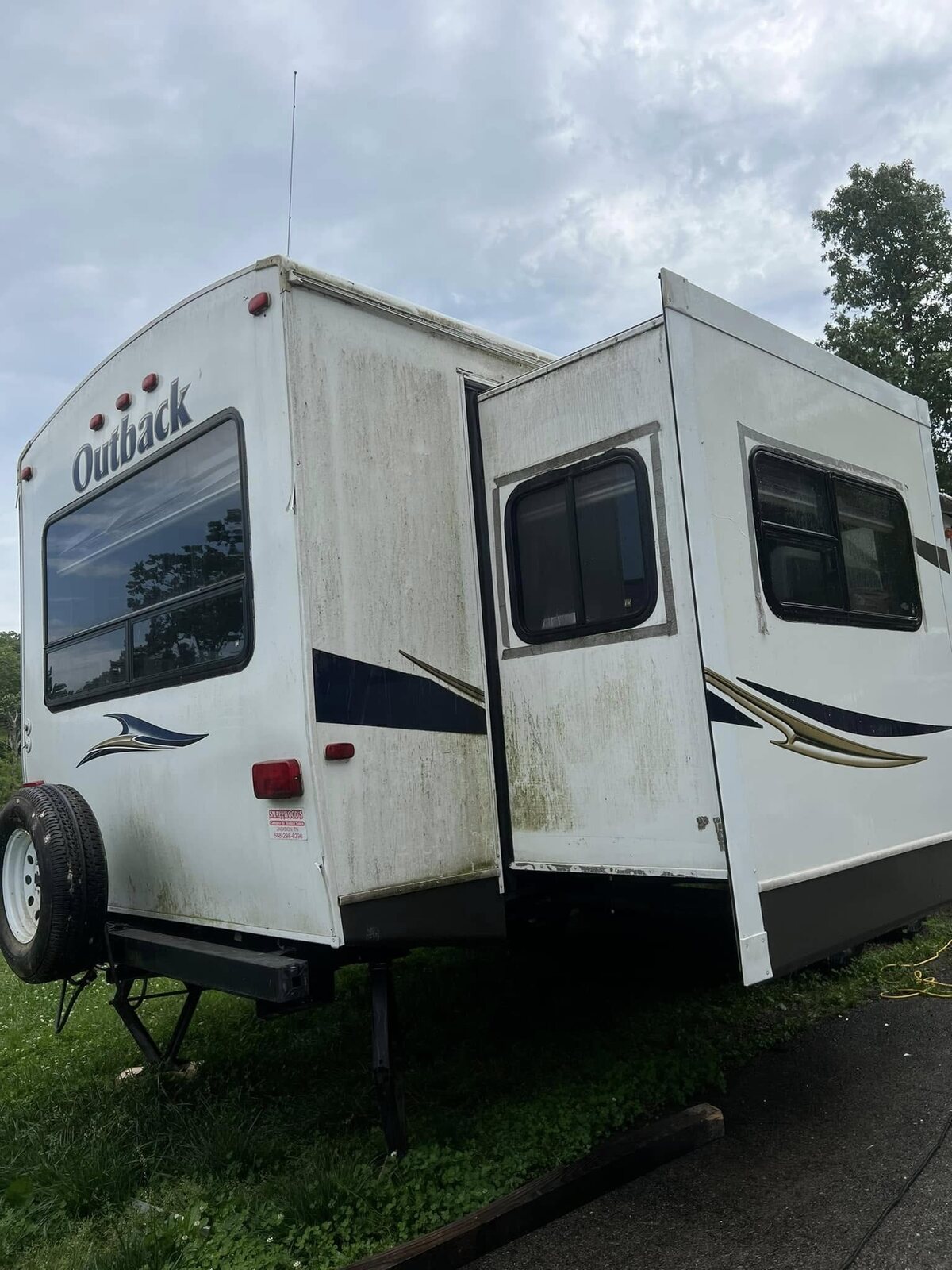 Travel trailer with heavy green and black algae streaking down the side before washing